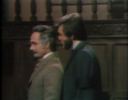 Evan (Humbert Allen Astredo), a young lawyer with a Charles Dickens beard, stands in Collinwood House looking ambivalently guilty. Quentin Collins (David Selby), a Dashing Anti-Hero with huge sideburns and huger bisexual bad guy energy, stands well under an inch behind him and quips into his ear 