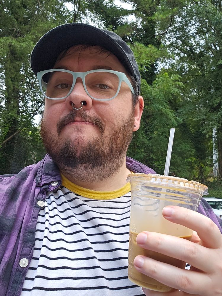 Bearded person with iced coffee