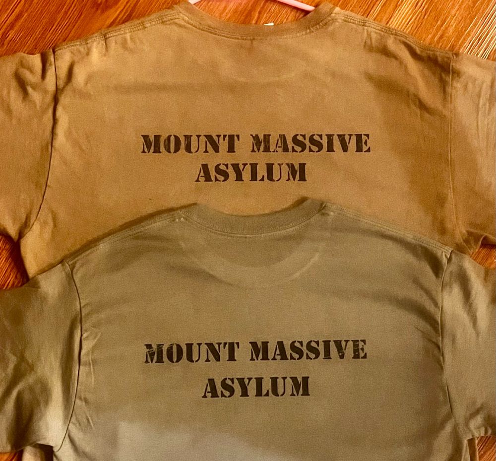  A pair of greenish-grey size L T-shirts, turned over to show off "Mount Massive Asylum" printed across the back in black stencil font. 