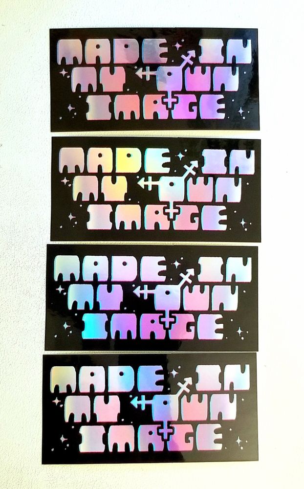 A row of holographic stickers reading 'MADE IN MY OWN IMAGE' where the O is the trans symbol.