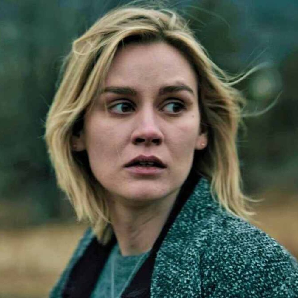 Blonde woman standing outside, looking very worried. 