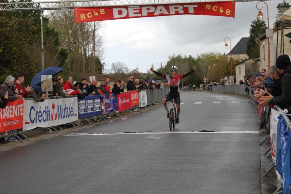 Alfie crossing the line alone with his hands high on a wet road.