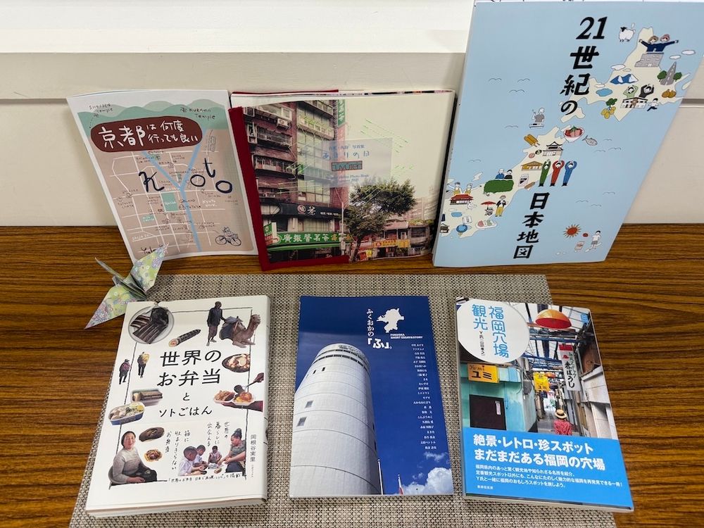 テーブルの上に以下の本が並べてあります。
『京都は何度行っても良い』Yule.Y
『あまりの日』浮遊点/いつき　
『「21世紀の日本地図」歩いて日本一周して作ったガイドブック』 平井佑樹 巡風社
『世界のお弁当とソトごはん』岡根谷 実里 三才ブックス
『ふくおかの「ふ」』
『福岡穴場観光 (KanKan Trip Japan 5)』Ｙ氏（山田孝之）書肆侃侃房
