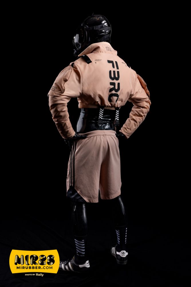 Choose your drone, this one comes in a pastel cyberpunk meets scaly variety. Wearing a black latex base with pink tech wear and white strips for trim, Adidas Superstars for footware. Posing hands on the hips, back to the camera with FBRC written down the spinal column of the crop top jacket.