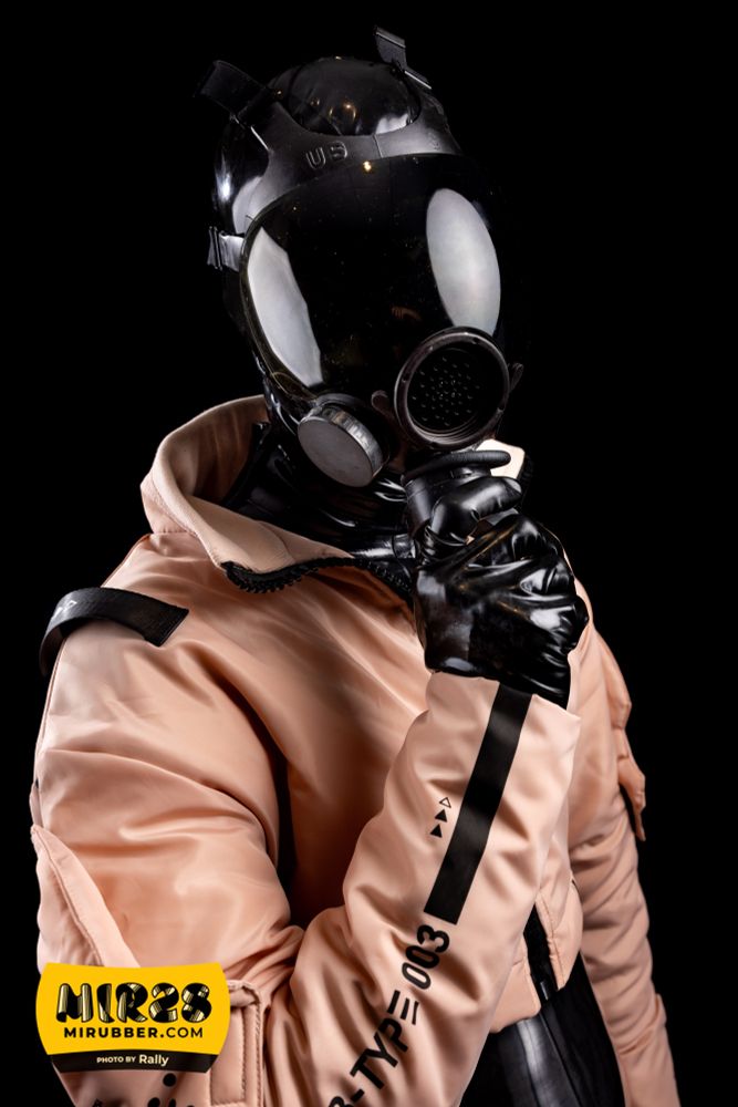 Rubber drone in a thought provoking pose, as if it can think, please... Wearing a black latex catsuit under pink tech wear with an MSA gasmask.