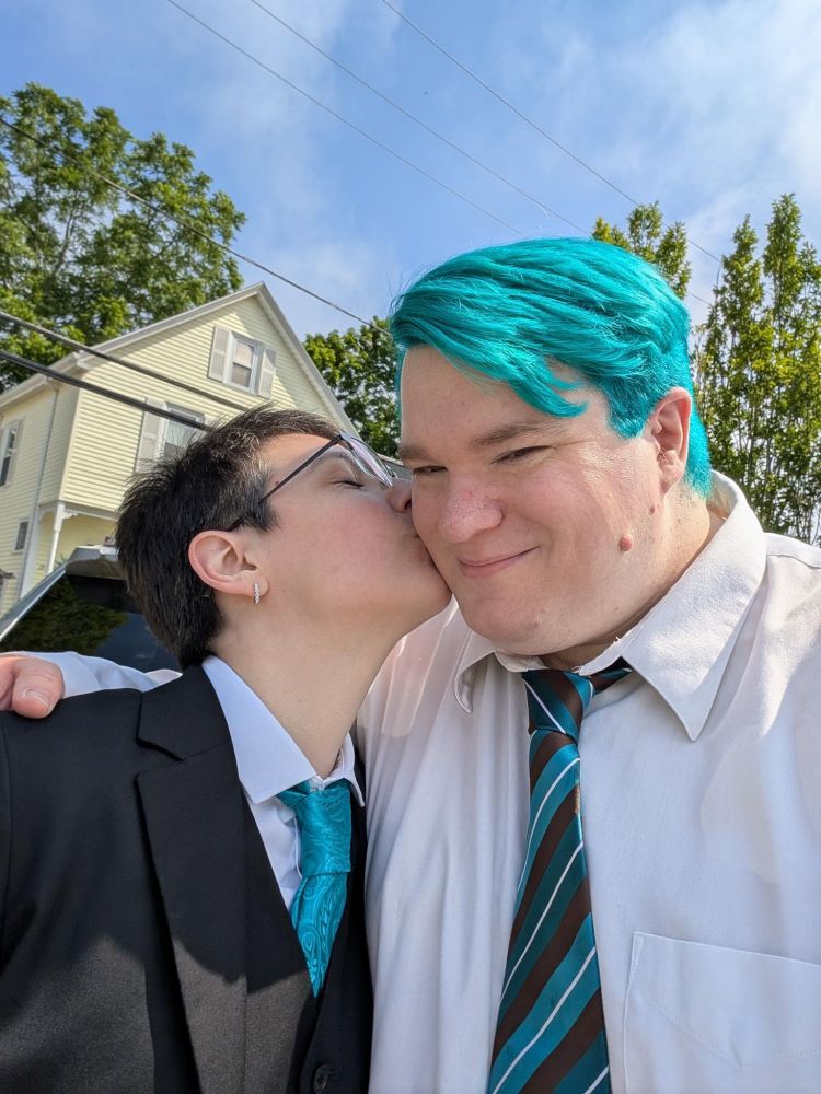 I am kissing my spouse's cheek. It has bright teal hair and a teal striped tie. My teal tie matches its hair.