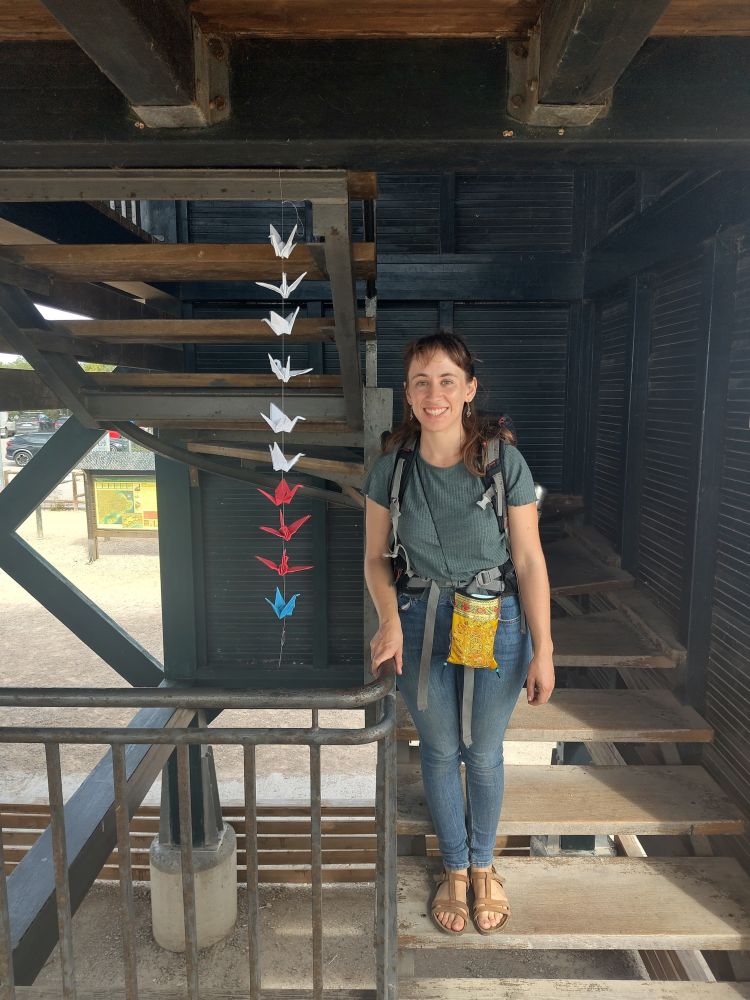 Artist standing in front of a skein of origami cranes representing endangered birds