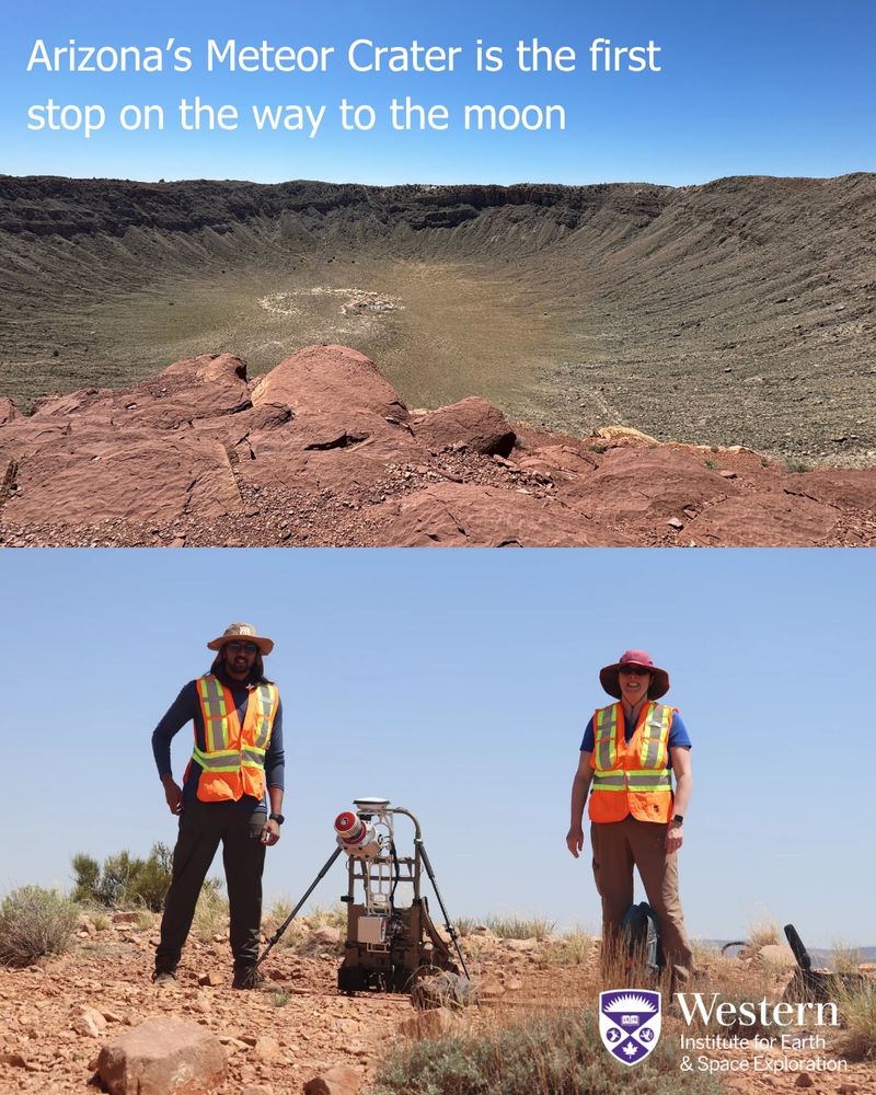 two scientists stand infront of an impact crater with equipment in the foreground. 