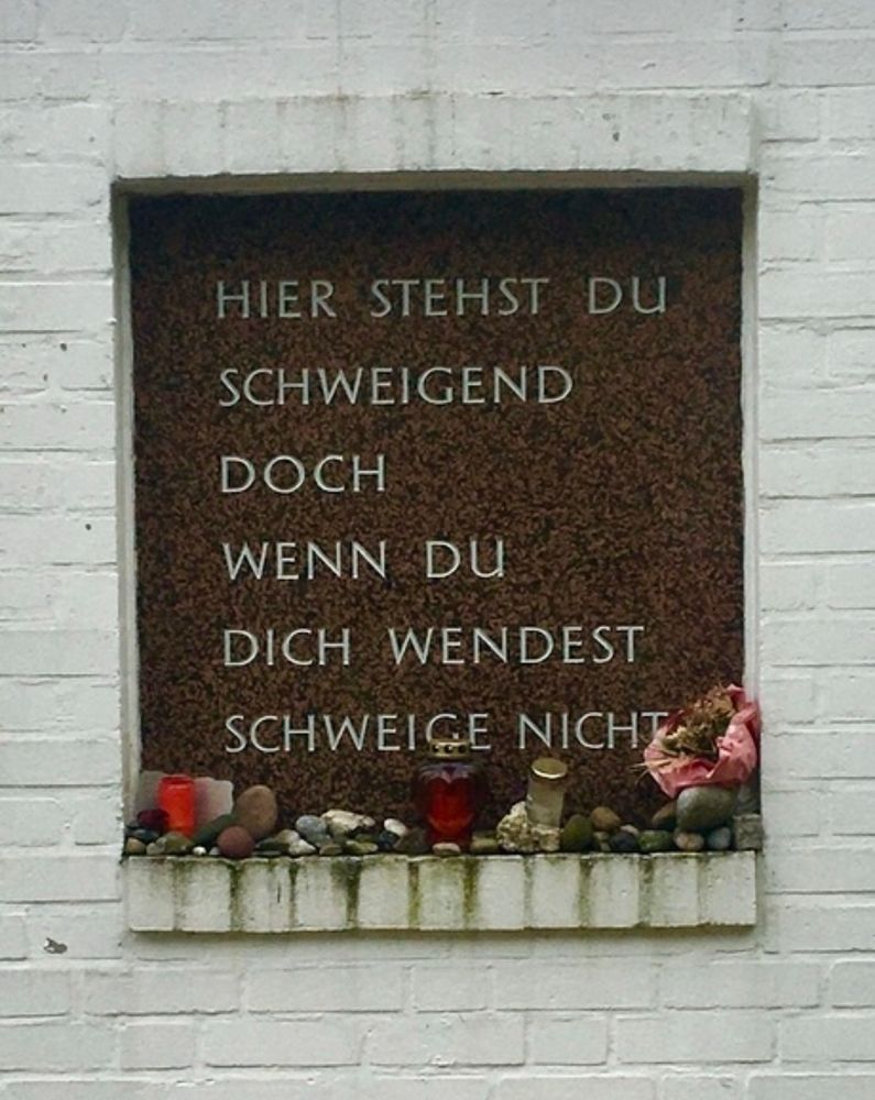 Die Tafel im Rosengarten der Gedenkstätte am Bullenhuser Damm, Hamburg. Die Inschrift lautet „Hier stehst du schweigend doch wenn du dich wendest schweige nicht“. 