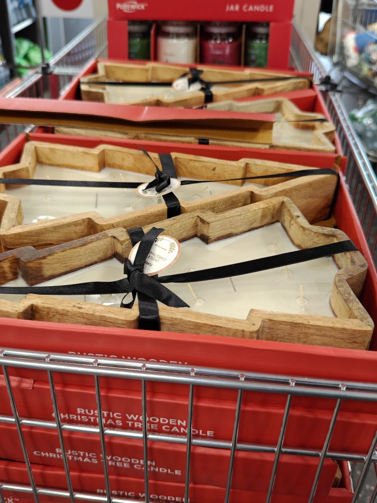 A large christmas tree shaped candle with a wooden frame
