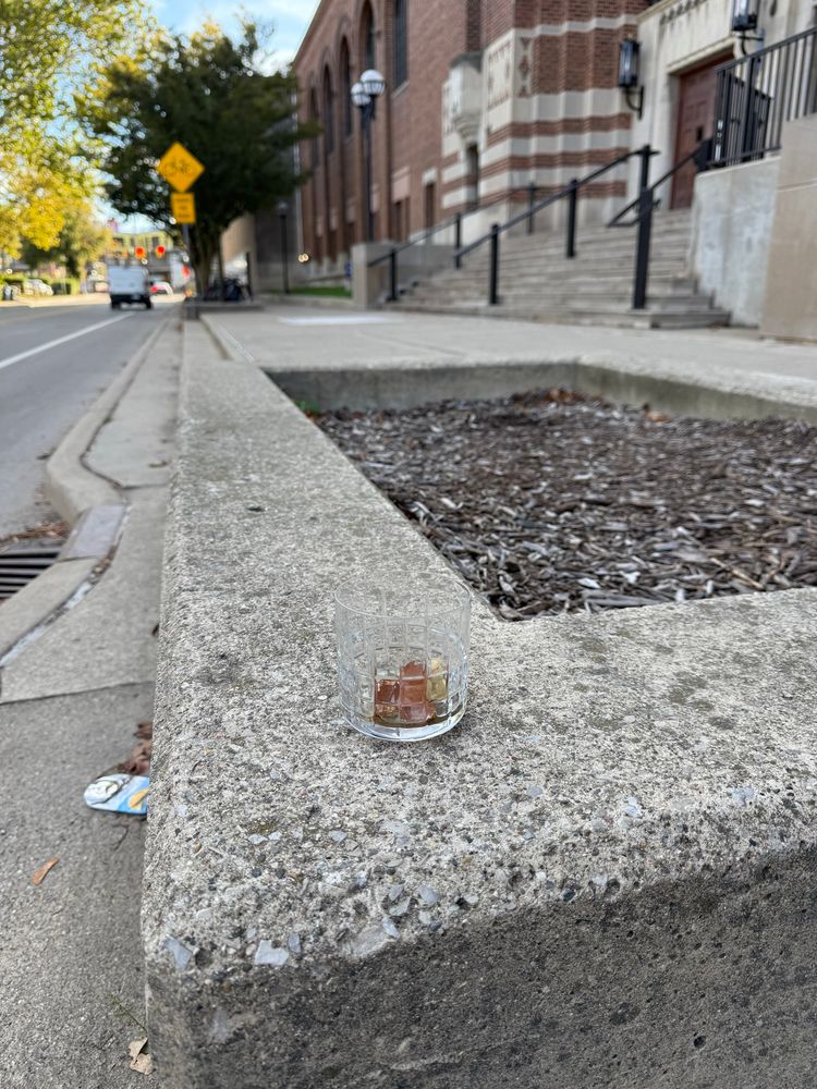 A fancy glass sitting on a concrete curb/planter outside of the IM building.