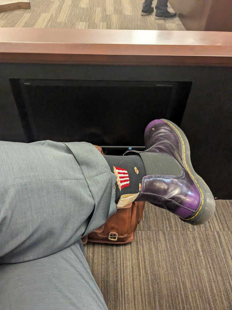 View of lawyer wearing marginally appropriate footwear sitting in a jury box.