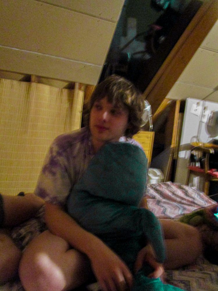 A blurry indoor photo of me holding a large blåhaj at a cozy gathering.