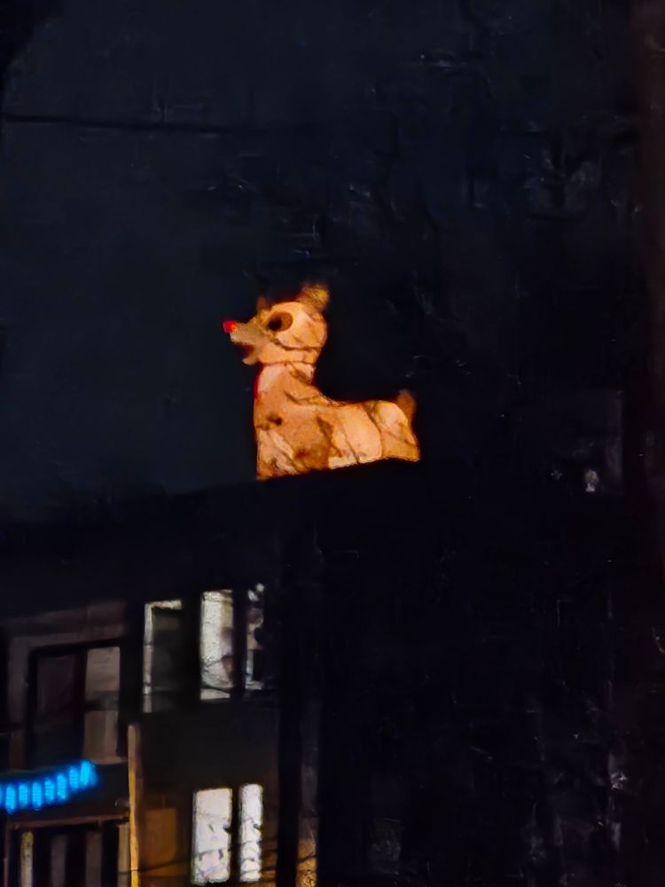 A giant Rudolph blow up is lit and on top of a house
