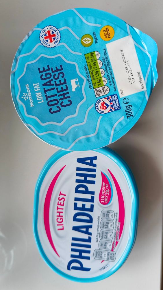 Two pots of cheese such as might be used to torture someone who likes cheese. One is "lightest" Philadelphia soft cheese. The other is low fat cottage cheese. 
