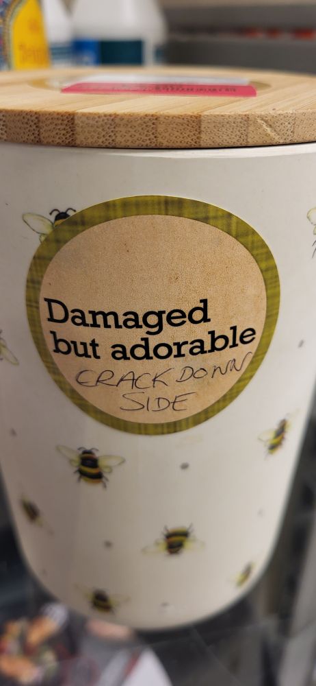 A jar with a sticker on it reading 'Damaged but adorable. Crack down side.'