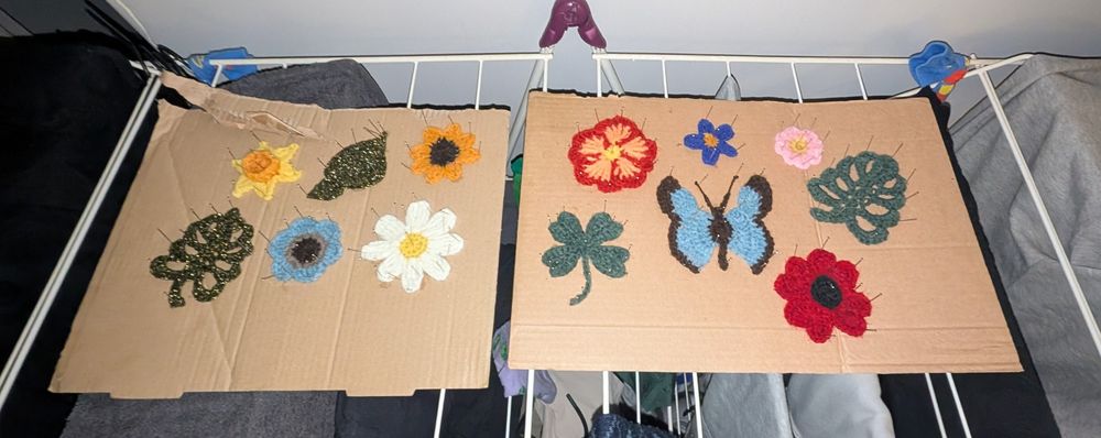 petites fleurs et feuilles et papillon en crochet de diverses couleurs qui sèchent sur du carton sur un tancarville 