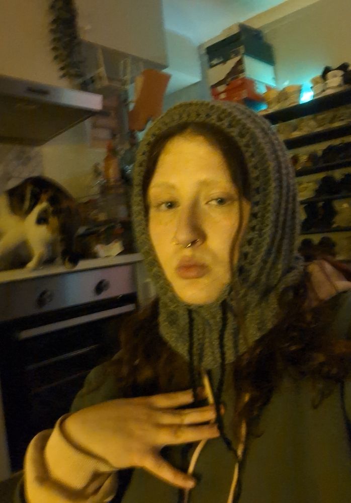 selfie de moi même avec ma balaclava (?) en crochet (gris avec un cordon noir) que j'ai réalisé aujourd'hui ainsi qu'avec mon chat en fond 