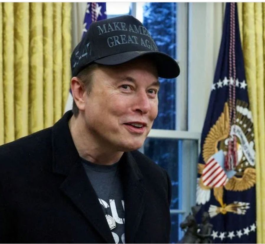 Musk in Oval Office with black MAGA hat, T-shirt, and yes, a black sport coat. The new Republican suit.