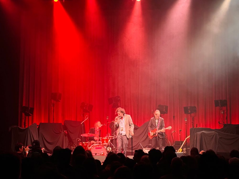 A drummer, singer, and guitarist onstage performing. 