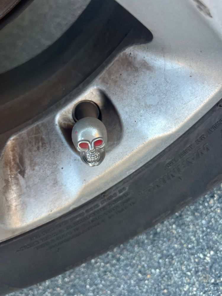 Valve stem cap that’s a metal skull with red gem eyes 
