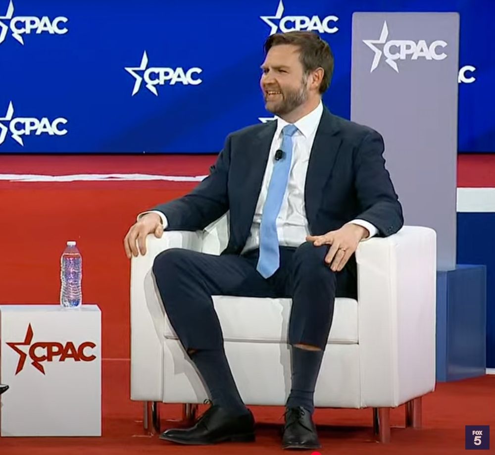 Jants-Dance Vance sitting in a chair with his suit pants riding up almost to his goddamn kneecaps. 