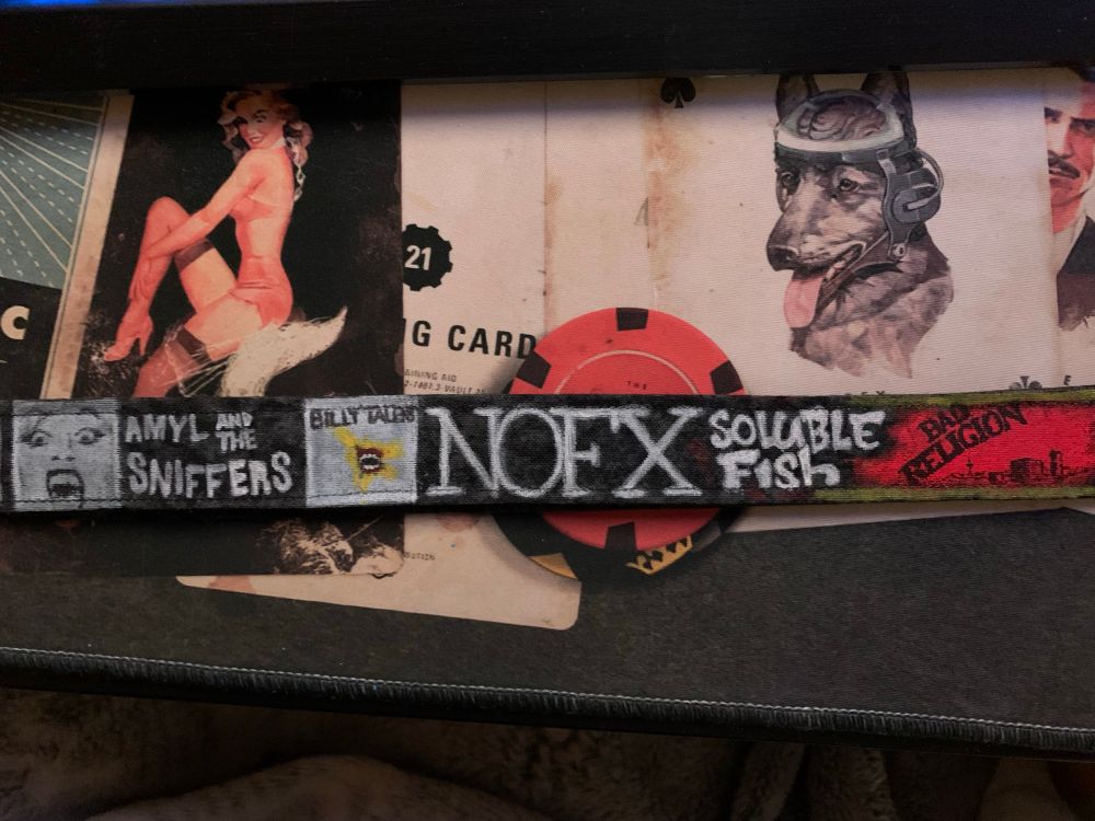 Paintings on a black lanyard that read "Amyl And The Sniffers", "Billy Talent", "NOFX", "Soluble Fish", and "Bad Religion".