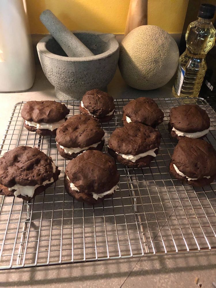 A photo of homemade whoopie pies. A layer of vanilla icing/filling is sandwiched between two chocolate cookies. 