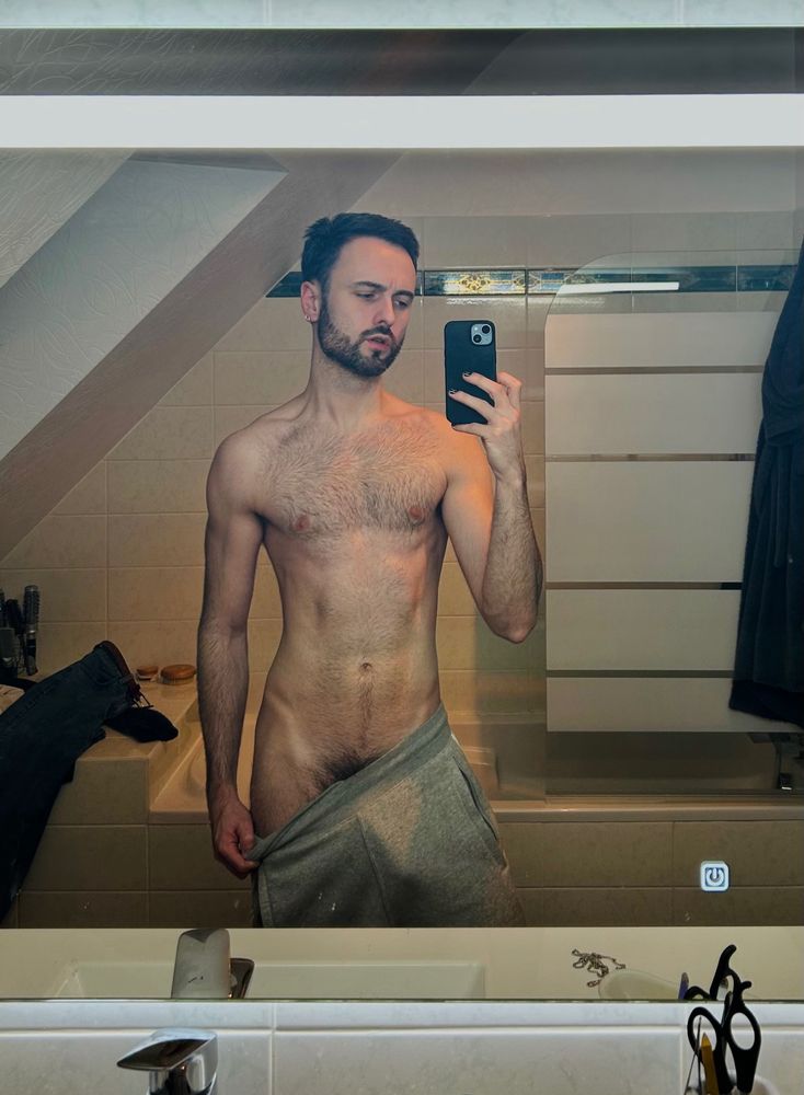Selfie miroir. Un homme dans une salle de bain. Un jogging gris.