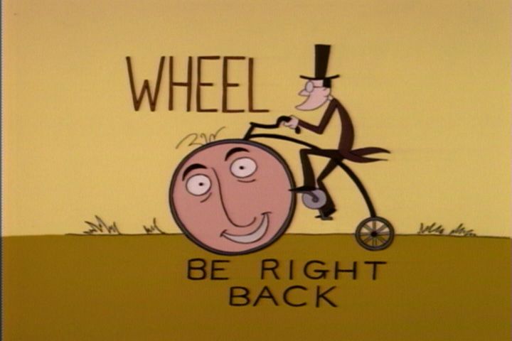 Screenshot of a “technical difficulties” splash screen from The Critic. Shows an old-timey art style of a Penny Farthing bike with the titular character’s face in the large wheel. Text reads “Wheel be right back”