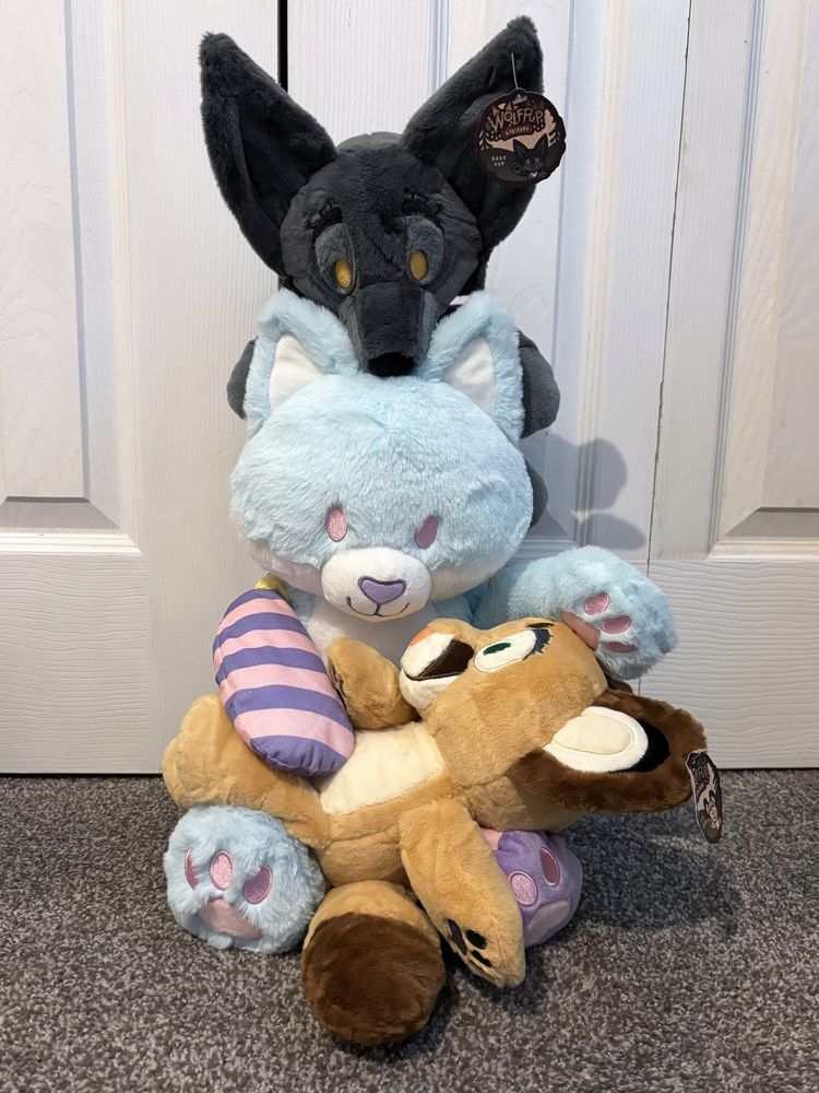 A pastel blue fox Patchkin plush sitting with a cougar in his lap and a black wolf on his head from Wolf Pup & Friends by Naomi Nao Romero!