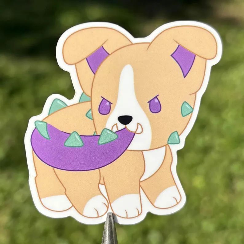 A photo of a vinyl sticker of Socks the American Pit Bull Terrier Puppysaur chewing his own tail with a determined expression.