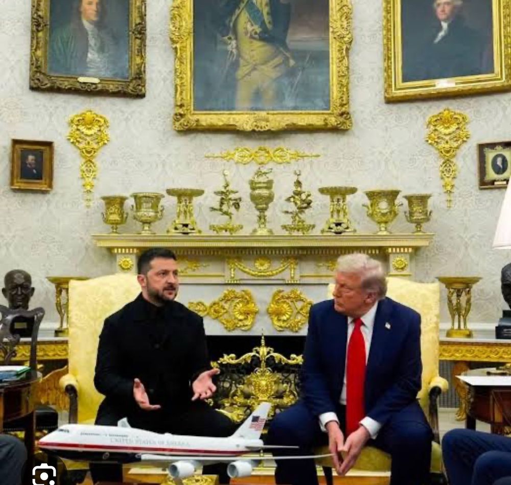 Volodymyr Zelensky and Donald Trump in the Oval Office surrounded by tacky “gold” knick knacks and wall decor