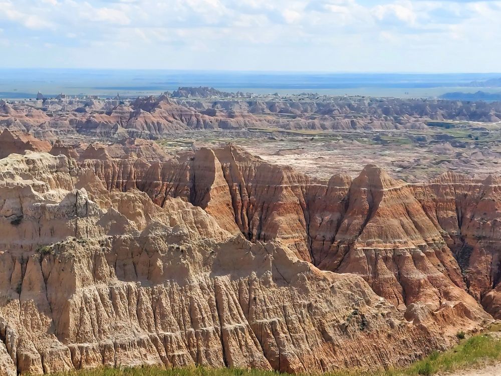 Much of the badland bedding of southwestern South Dakota is from the White River Formation of the late Eocene and early Oligocene Epochs (31-37 mya). The siltstone, claystone, and ash layers represent a floodplain environment with distant volcanoes. Badlands National Park, South Dakota, 30 Jul 2025.