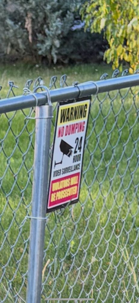 A zoomed in picture of the sign that says “warning no dumping”
