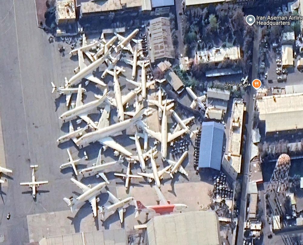 Screenshot of google maps satellite view showing about 30 airplanes wedged in with each other in a VERY tight parking configuration