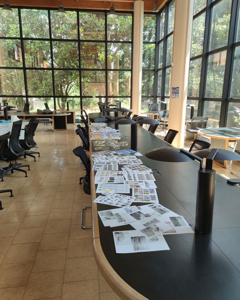 Vue de la salle de lecture vitrée, on y voit une imposante table sur laquelle recouverte de reproductions de fonds iconographiques issus de nos archives