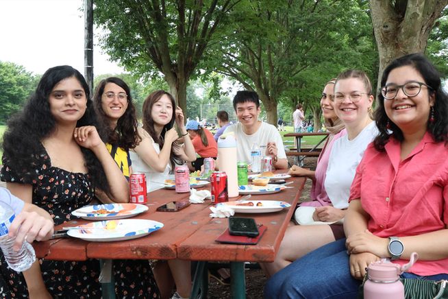 People posing for picture at picnic table.