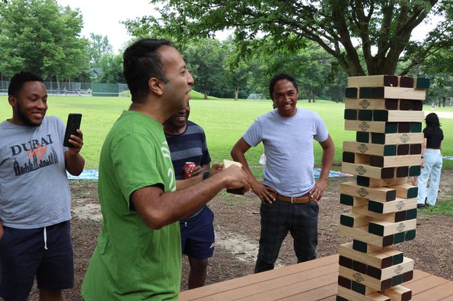 Person playing jenga and others watching.