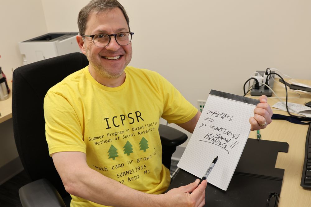 A man proudly holds up a math equation while smiling
