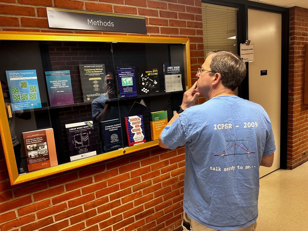 A man in front of a methods bookcase deciding which book to pick