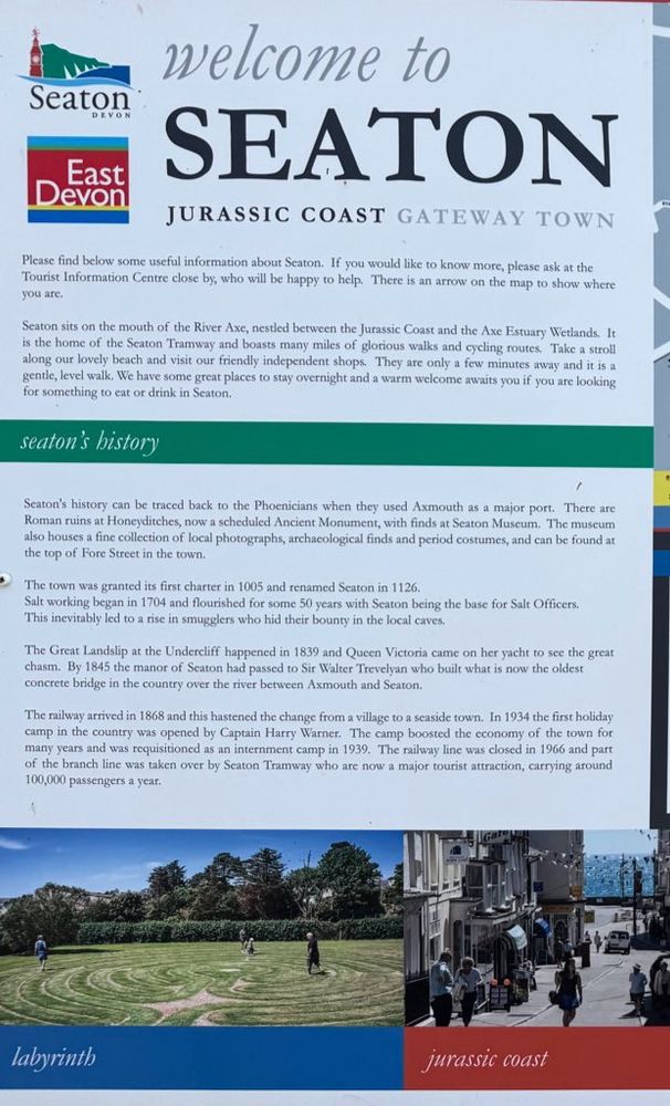 Seaton tourist information sign. Too much text to quote but it begins:

Seaton sits on the mouth of the River Axe, nestled between the Jurassic Coast and the Axe Estuary Wetlands. It is the home of the Seaton Tramway and boasts many miles of glorious walks and cycling routes. Take a stroll along our lovely beach and visit our friendly independent shops. They are only a few minutes away and it is a gentle, level walk. We have some great places to stay overnight and a warm welcome awaits you if you are looking for something to eat or drink in Seaton.

Seaton's history can be traced back to the Phoenicians when they used Axmouth as a major port. There are Roman ruins at Honeyditches, now a scheduled Ancient Monument, with finds at Seaton Museum. The museum also houses a fine collection of local photographs, archaeological finds and period costumes, and can be found at the top of Fore Street in the town.