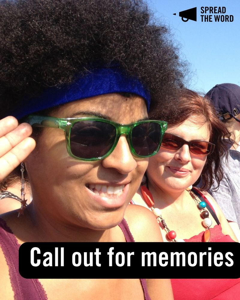 1. Two women sit smiling to camera. The woman on the left has an afro and wears green-rimmed sunglasses, she is saluting and has a cheesy grin. The woman next to her has dark red sunglasses and wears lots of beads
