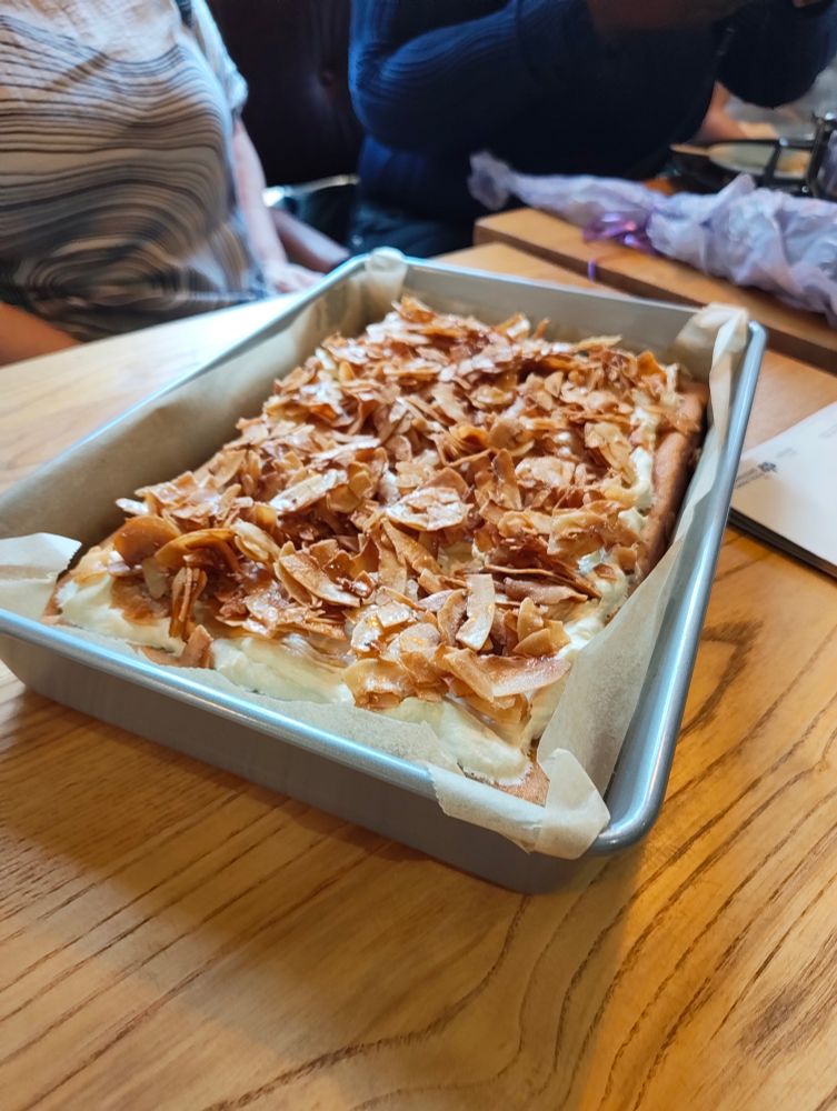 A picture of a cake in a tin, with cocounut flakes all over the top