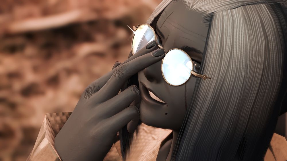 Closeup shot of Jahilia's face. The colour is washed out of the shot, and she's grinning as she pushes her glasses up with a gleam