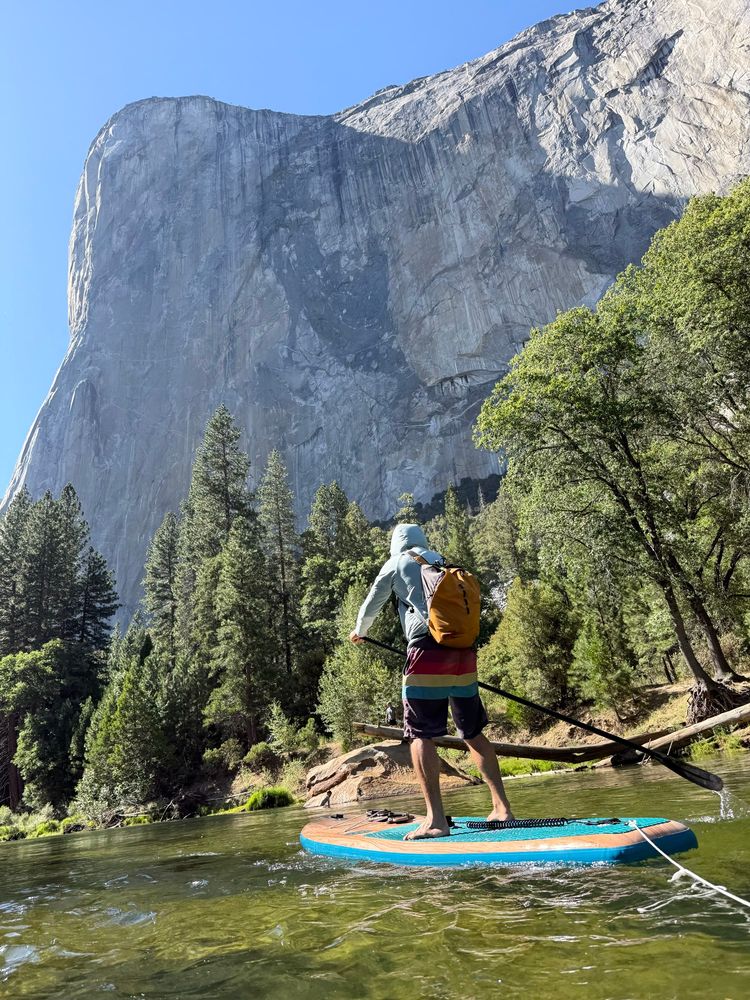Person on a paddleboard on the Merced River with the granite monolith El Capitan rising above in the background