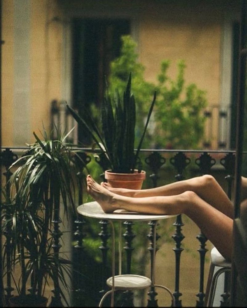 Marjorie Kempf photographe 
Sur un balcon les jambes d’une femme assise repose sur une table en fer forgé.