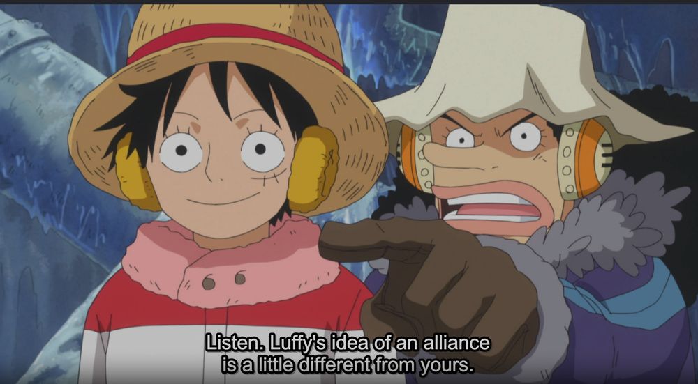 a screenshot of the One Piece anime, with Usopp and Luffy in winter gear. Usopp points over Luffy's shoulder at someone offscreen and says, "Listen, Luffy's idea of an alliance is a little different from yours." Luffy smiles blankly