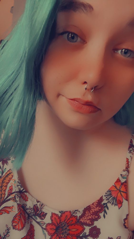Pale femme with blue hair smiles at the camera.