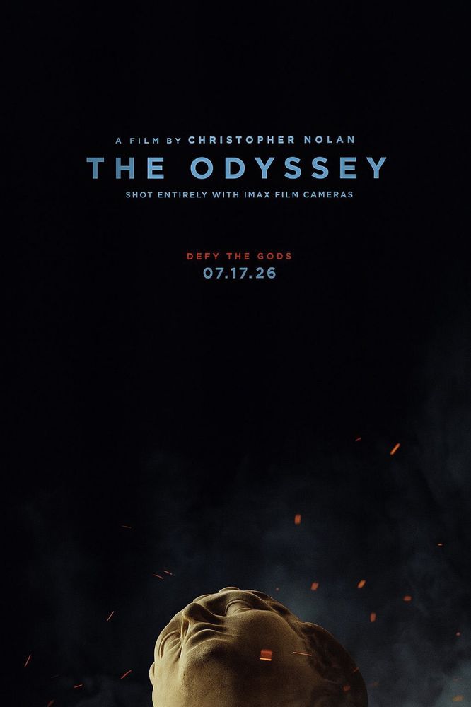 Affiche très sobre, fond noir. En haut "A film by Christopher Nolan. The Odyssey. Shot entirely with imax film cameras" en bleu clair, puis "Defy the gods" en rouge et la date de sortie "07.12.26" en bleu. En bas de l'affiche entourée de fumée et de braises qui vole dans l'air, une tête de statue tombée en arrière comme cassée,  en écho au "défi les dieux" adressé à Ulysse et aux spectateurs.  